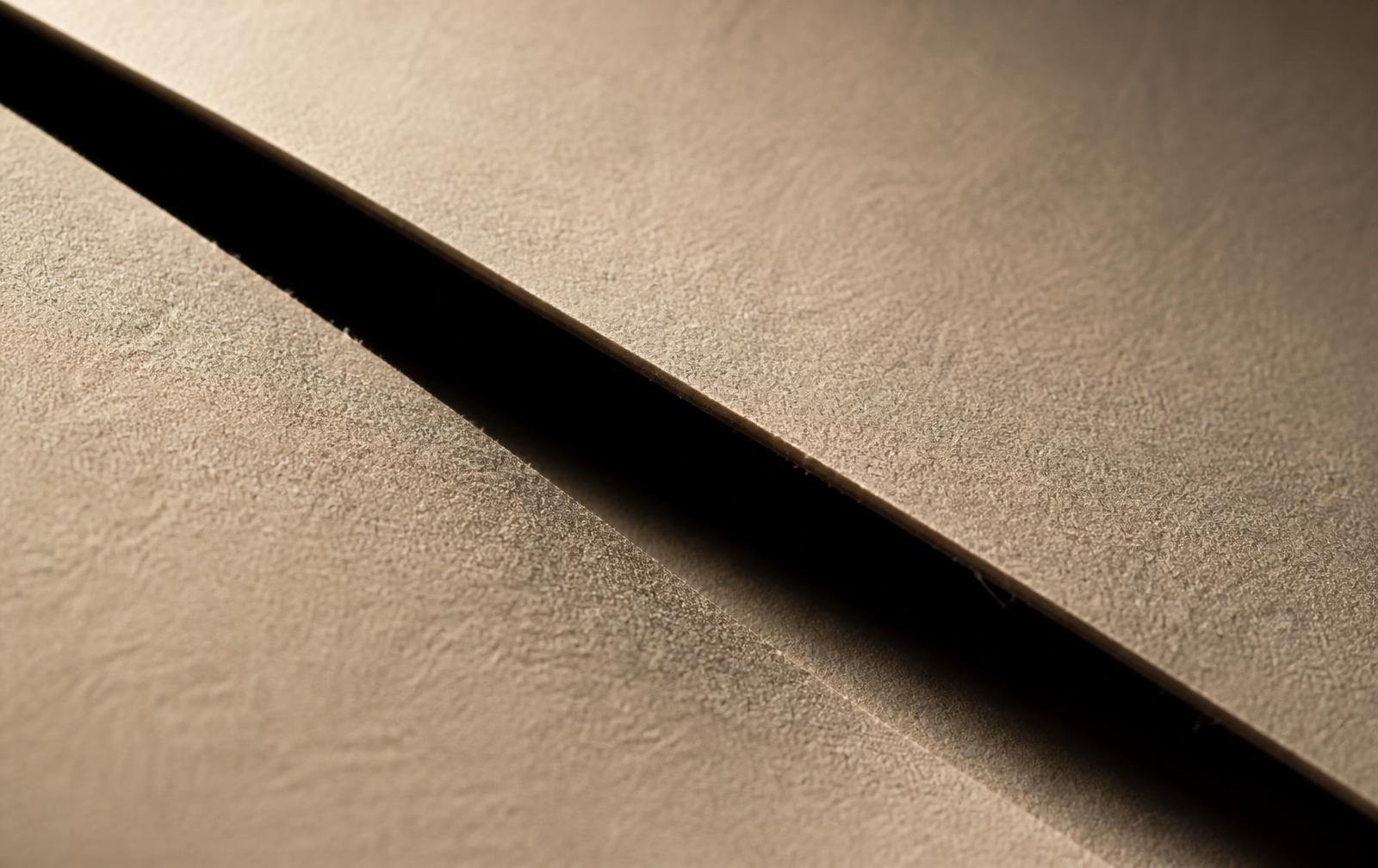 A sheet of ivory paper cut cleanly by a single diagonal slice